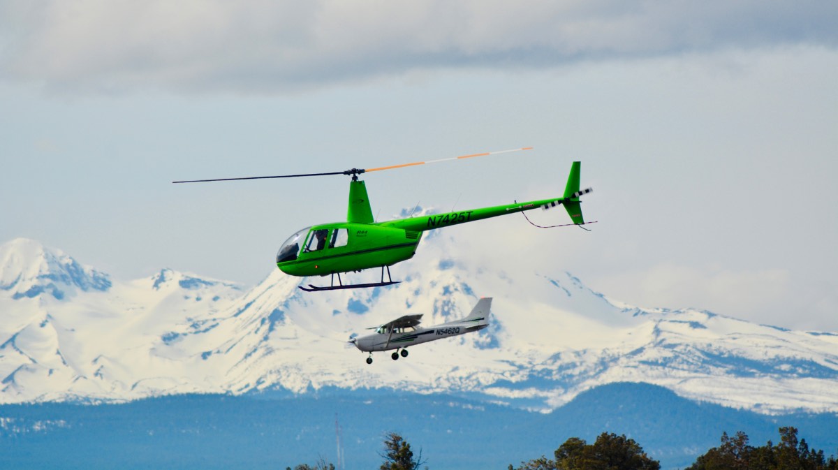 helicopter pilot vs. airplane pilot flying next to each other with mountains in the background