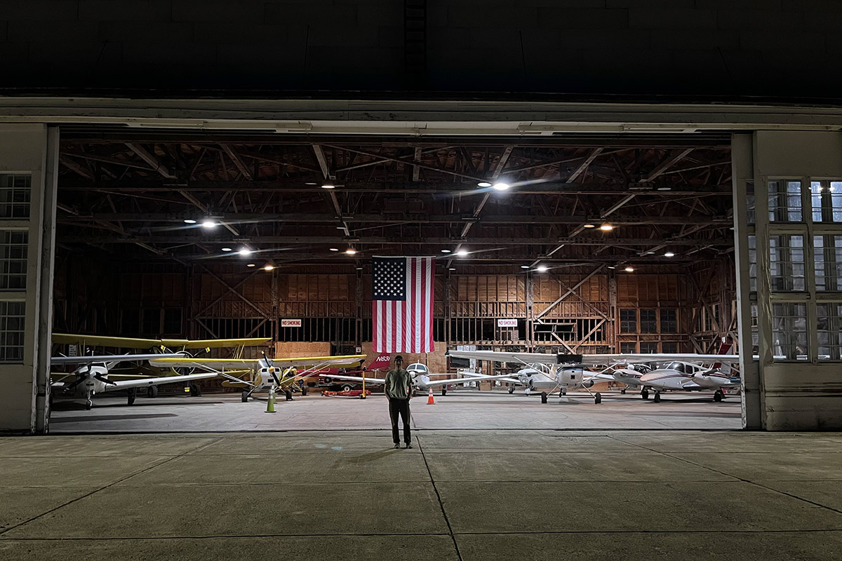 Person standing in front of helicopter garage with an american flag for a blog about federal aviation regulations