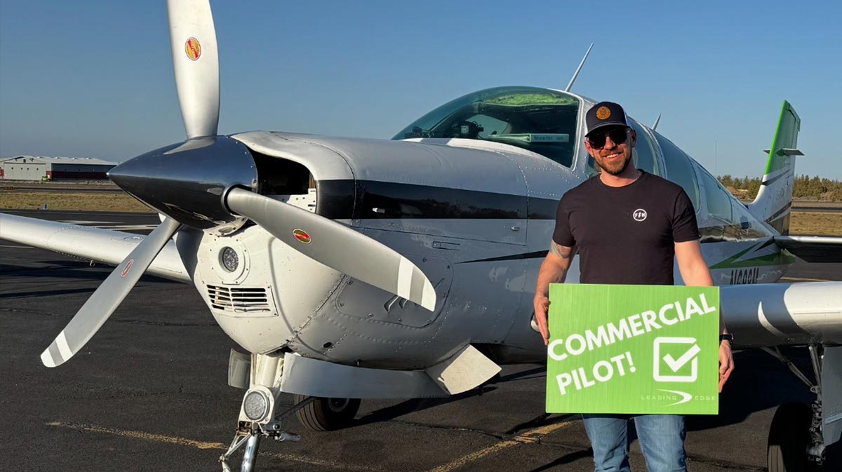 pilot standing next to helicopter with a "commercial pilot" sign for a blog about commercial pilot ground school